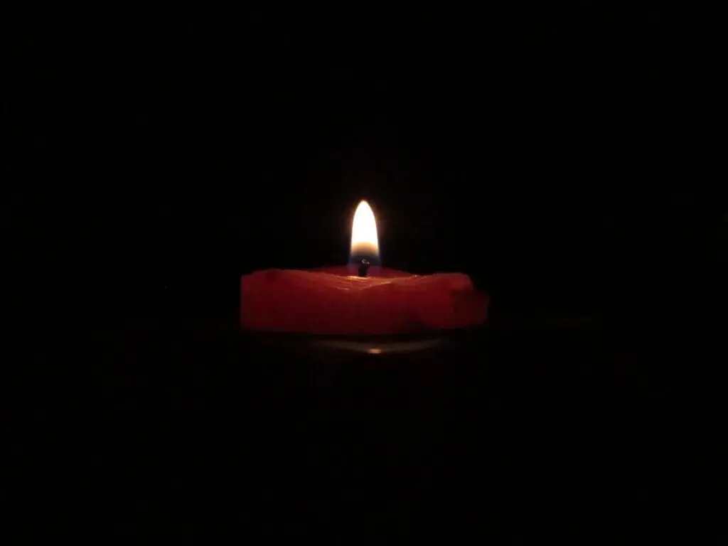 red lighted candle on dark room